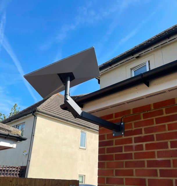 Starlink satellite dish wall-mounted on red brick with a tidy black bracket and cable route
