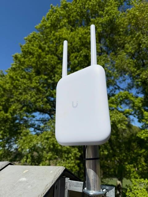 Outdoor Ubiquiti UniFi access point on a metal pole for garden and outdoor WiFi coverage