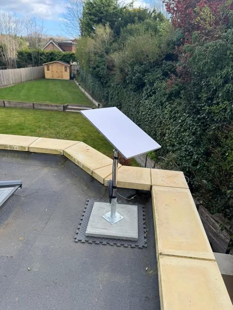 Starlink dish on a flat roof with a concrete ballast mount and neat cable management