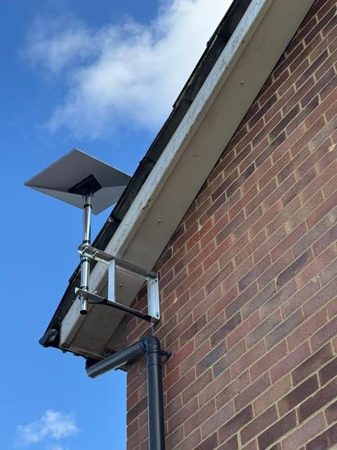 Starlink satellite dish installed high on a brick house with a wall-mount bracket