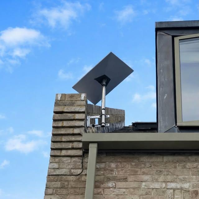 Starlink dish pole-mounted on a brick chimney with clear sky line of sight