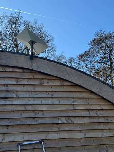 Starlink dish mounted on a curved wood-clad building during a professional install